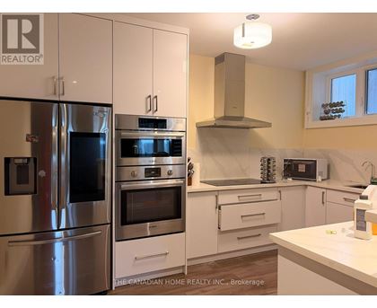 A kitchen with a refrigerator, oven, and microwave.