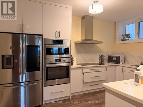 A kitchen with a refrigerator, oven, and microwave.