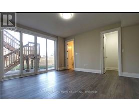 A room with a wooden floor and a sliding glass door leading to a deck.
