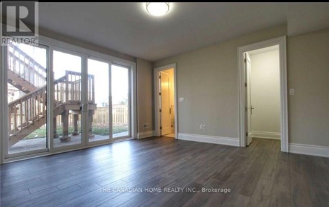 A room with a wooden floor and a sliding glass door leading to a deck.