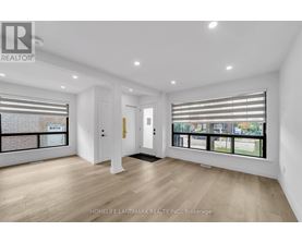 A spacious room with wooden flooring and large windows.
