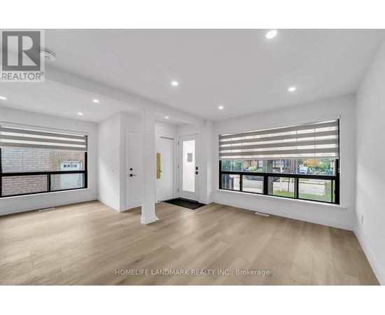 A spacious room with wooden flooring and large windows.