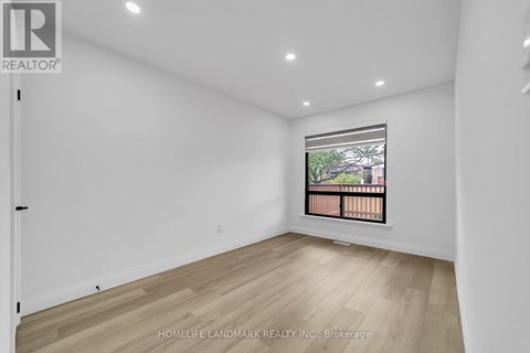 A room with a window showing a balcony with a view of trees and a building.