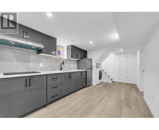 A modern kitchen with wooden floors and grey cabinets.
