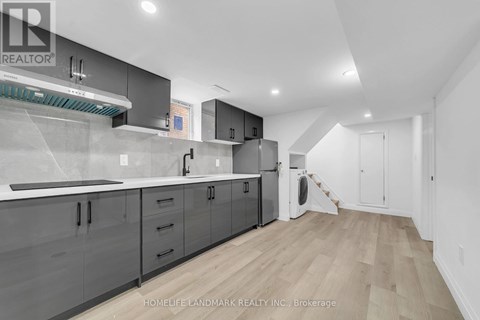 A modern kitchen with wooden floors and grey cabinets.