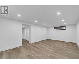 A spacious room with wooden flooring and white walls.