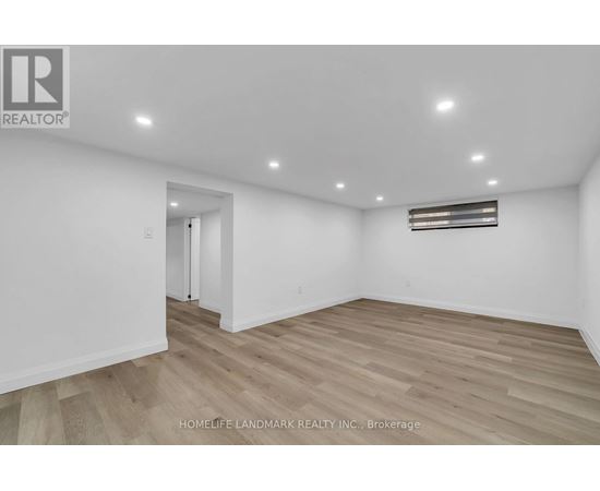 A spacious room with wooden flooring and white walls.