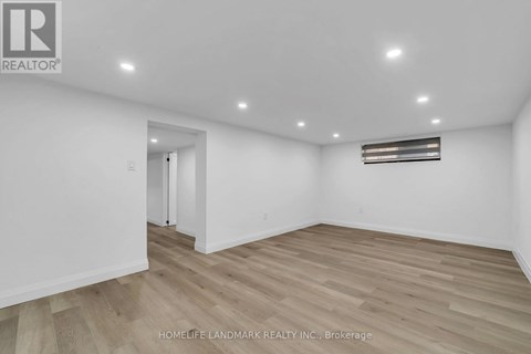 A spacious room with wooden flooring and white walls.