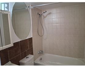 A bathroom with a toilet, tub, and mirror.