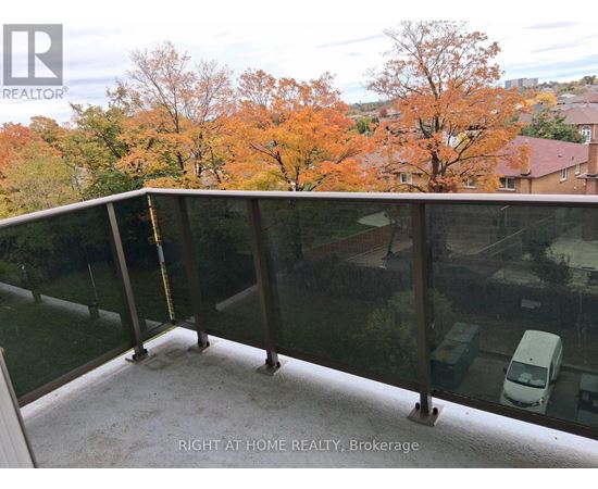 A balcony with glass railings overlooking a residential area.