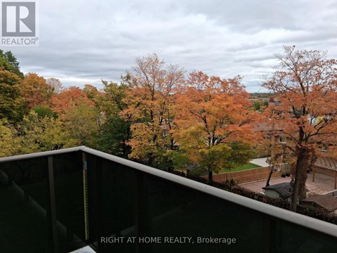 A view from a balcony of a residential area with trees in autumn colors.