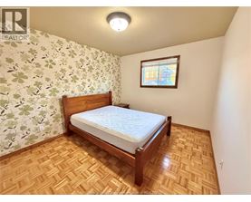 A bedroom with a wooden bed and a window with a stained glass design.