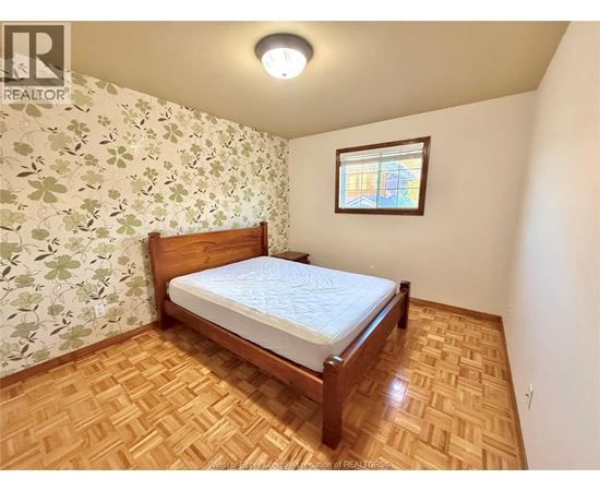 A bedroom with a wooden bed and a window with a stained glass design.