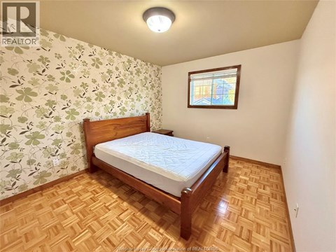 A bedroom with a wooden bed and a window with a stained glass design.