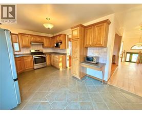 A kitchen with wooden cabinets and a tile floor.