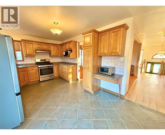 A kitchen with wooden cabinets and a tile floor.