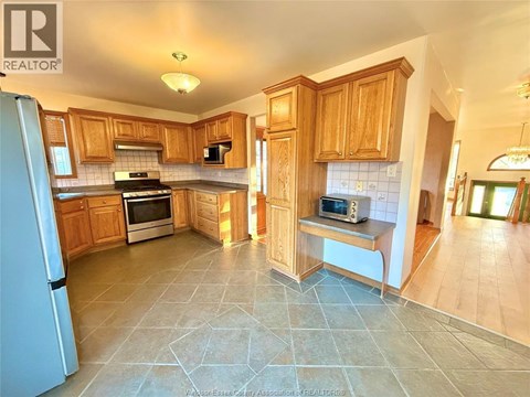 A kitchen with wooden cabinets and a tile floor.