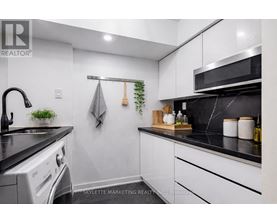 A modern kitchen with white cabinets and black countertops.