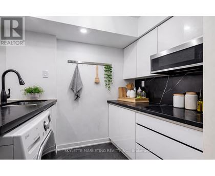 A modern kitchen with white cabinets and black countertops.