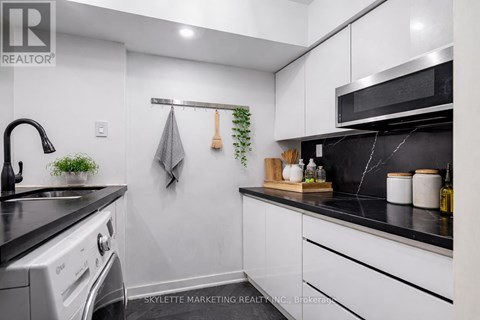 A modern kitchen with white cabinets and black countertops.