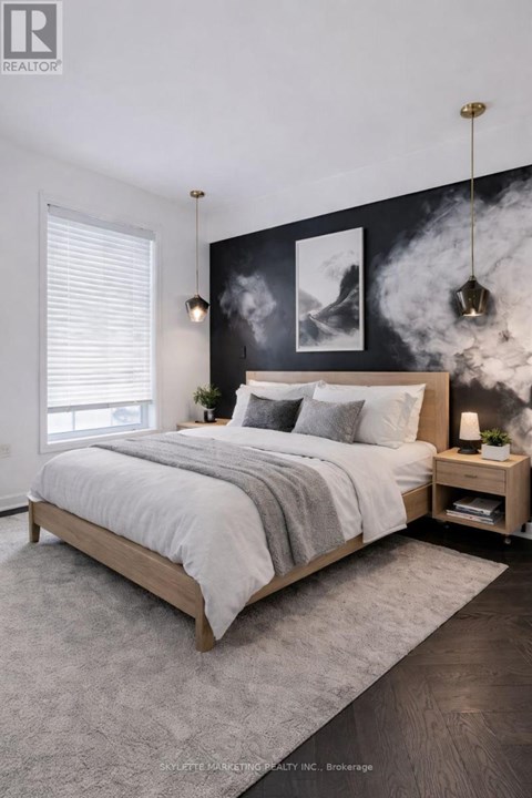 A bedroom with a large bed and a black and white artwork on the wall.