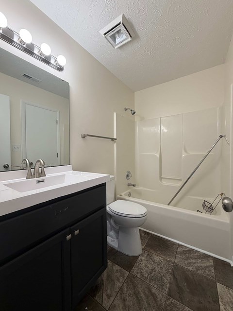 A white sink with a silver faucet is on a counter with a mirror above it.