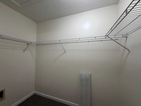 A white wall with a metal shelf on it.