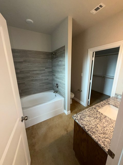 A bathroom with a stone wall and a white tub.