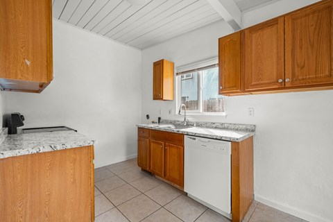 A kitchen with wooden cabinets and a white dishwasher.