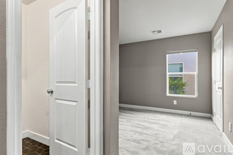 A room with a door and a window with a view of a building and trees.