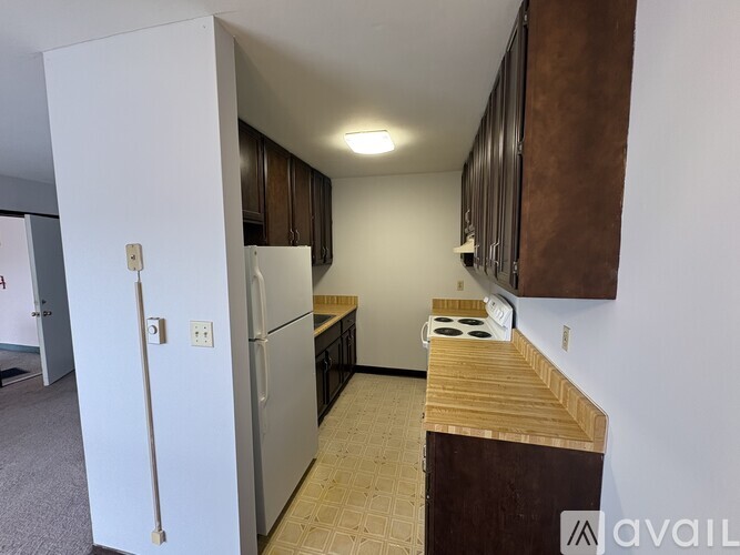 A kitchen with a white refrigerator and brown cabinets.