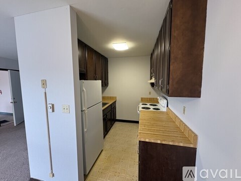 A kitchen with a white refrigerator and brown cabinets.