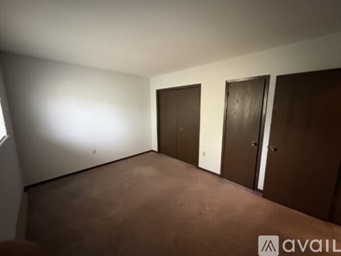 A room with brown carpet and three doors.