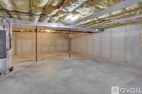 A spacious basement with a concrete floor and walls, and a furnace on the left side.