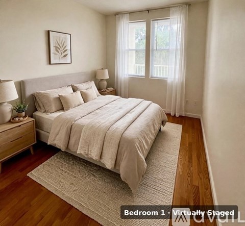 A bedroom with a large bed and a window with curtains.