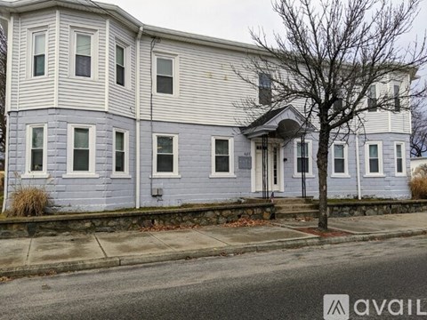 A two-story house with a front porch and a tree in front.