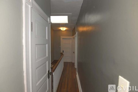 A hallway with a white door and a light on the ceiling.