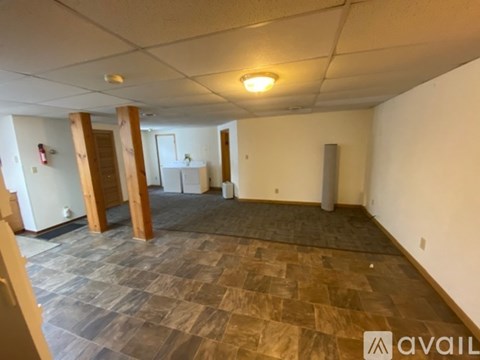 A spacious room with wooden pillars and a tiled floor.