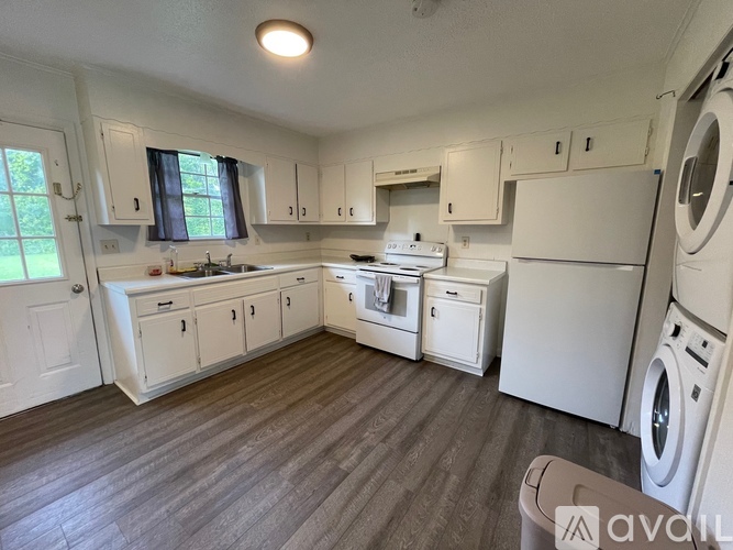 A kitchen with white appliances and wooden floors.
