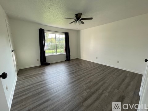 A room with a ceiling fan and a window with black curtains.