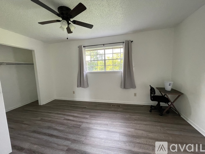 A room with a ceiling fan and a window with curtains.