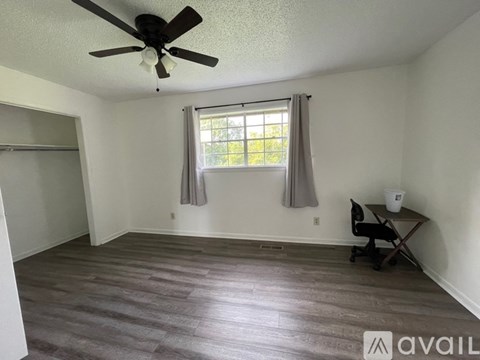 A room with a ceiling fan and a window with curtains.