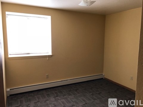 A room with a window and a carpeted floor.