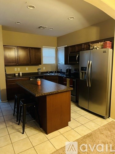 A kitchen with a brown island and a refrigerator.