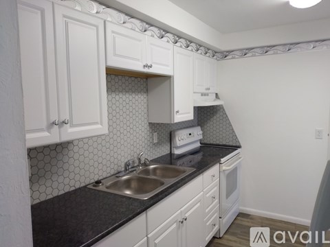A kitchen with white cabinets and a black countertop.
