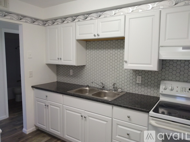 A kitchen with white cabinets and a black countertop.