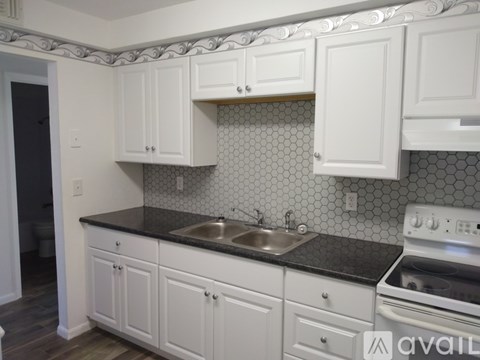 A kitchen with white cabinets and a black countertop.