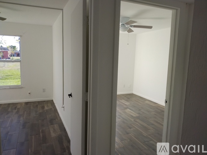 A room with a ceiling fan and wooden flooring.