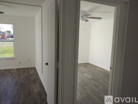 A room with a ceiling fan and wooden flooring.