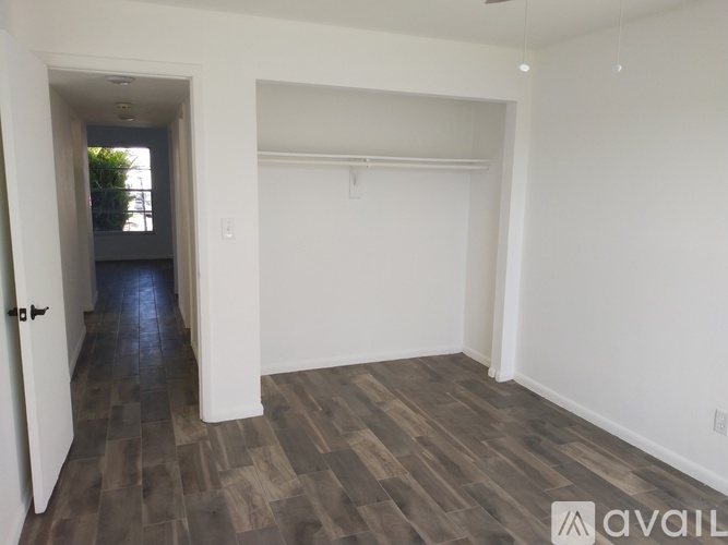 A room with wooden flooring and white walls is available for rent.